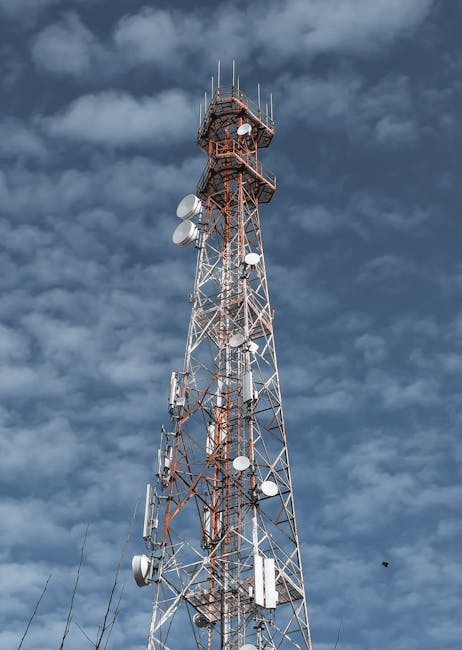 A telecommunications tower reaching into the cloudy sky, showcasing modern technology infrastructure.